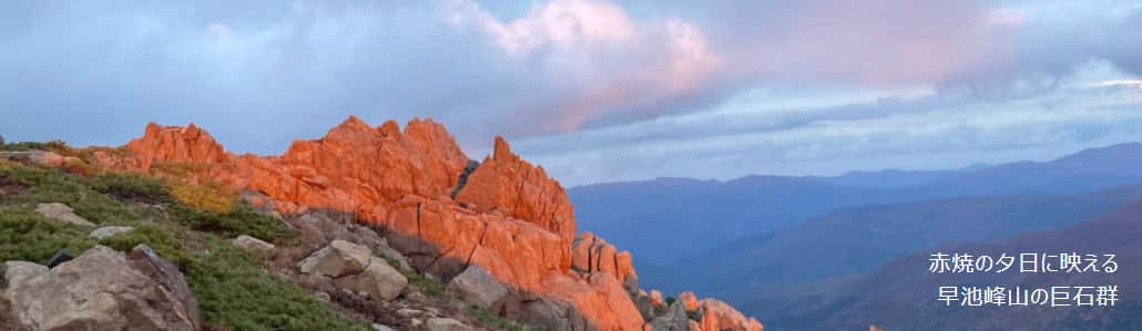 The massive rocks of Mount Hayachine stand out against the backdrop of the crimson sunset